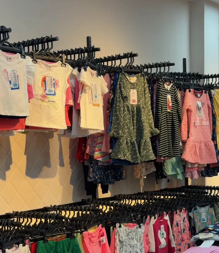 Araras com vestidos e camisetas infantis femininas na loja
